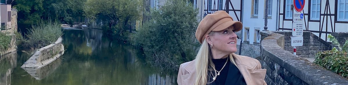 Julie standing on a bridge with a Monet-style river background in Luxembourg